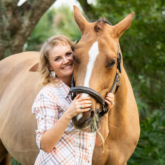 Jennifer Truett hugging a chestnut horse with greenery in the background